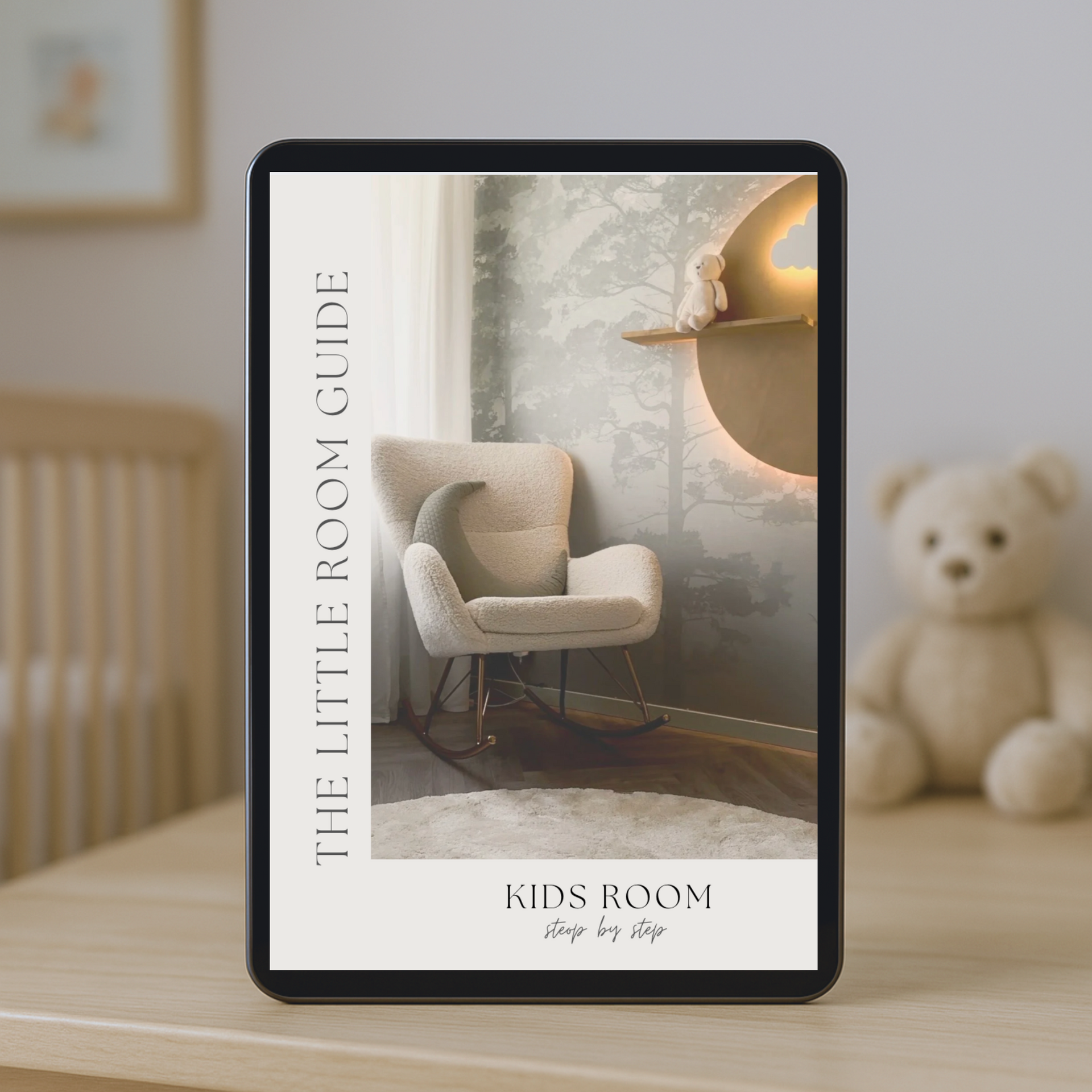 Tablet displaying 'The Little Room Guide' for kids room design on a wooden surface with a teddy bear in the background.
