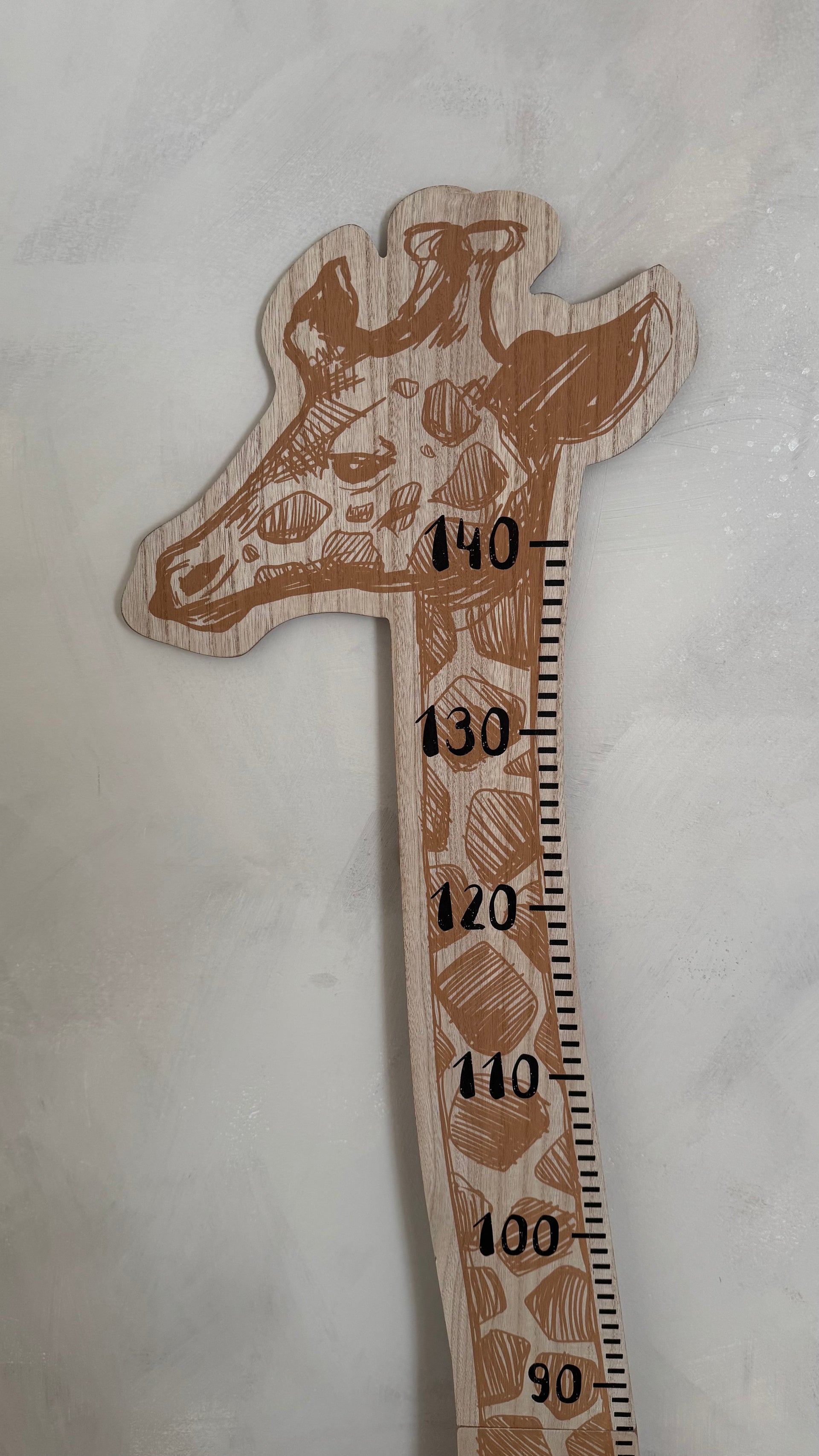 Wooden giraffe-shaped ruler with measurements on a light gray background